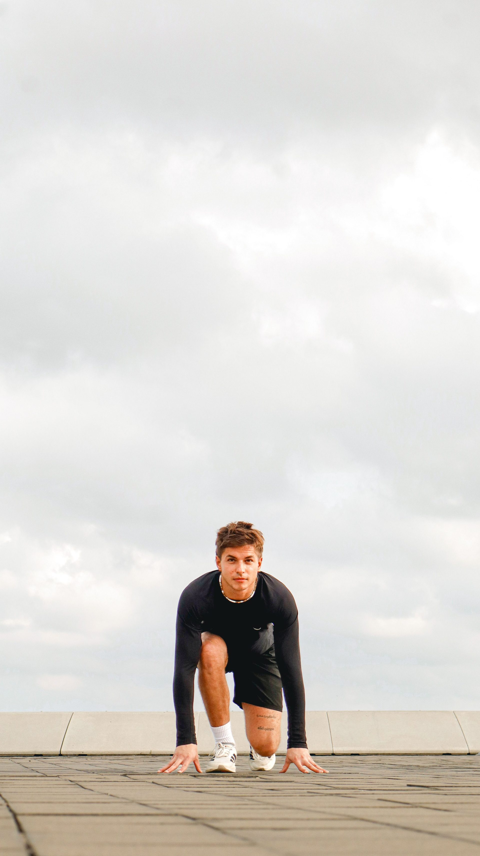 Focused athlete in a starting position on an outdoor track preparing for a sprint in España, showcasing determination.
