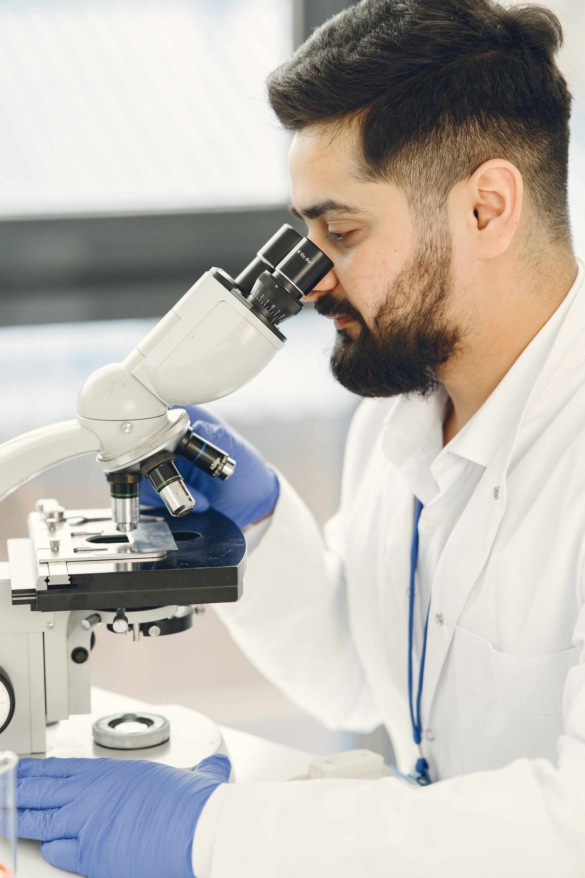 A scientist focused on examining samples through a microscope in a laboratory setting, showcasing scientific research and discovery.